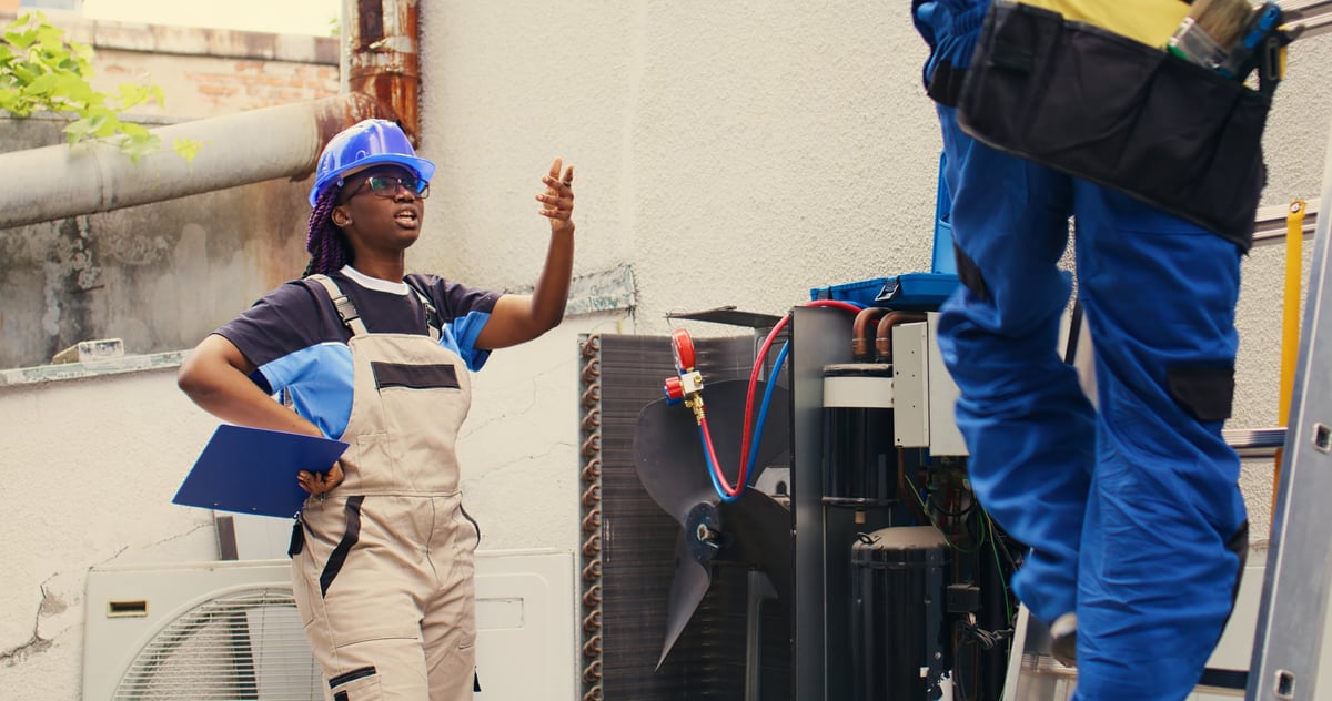 HVAC service manager coaching a technician in the field, reviewing service call process and documentation