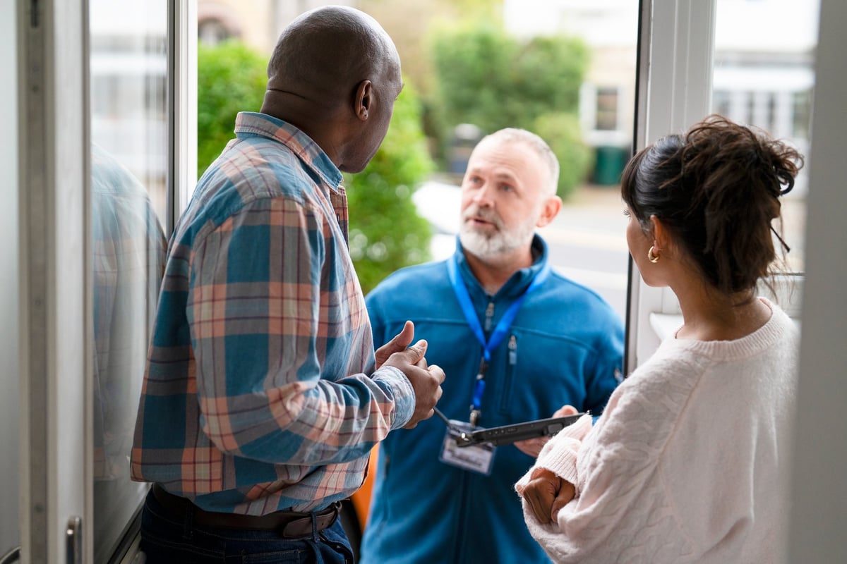 HVAC service professional calmly explaining findings to homeowners during a service visit, demonstrating trust-first communication