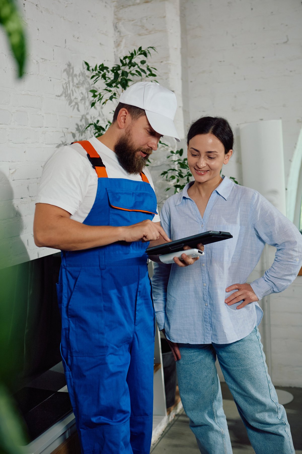 HVAC technician explaining service findings to a homeowner on a tablet — professional, trust-first communication