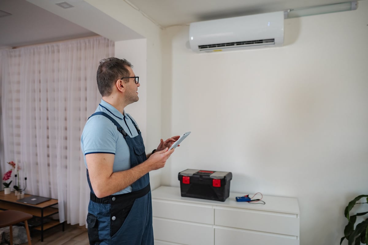 HVAC technician checking air conditioning unit using a digital tablet for maintenance and documentation